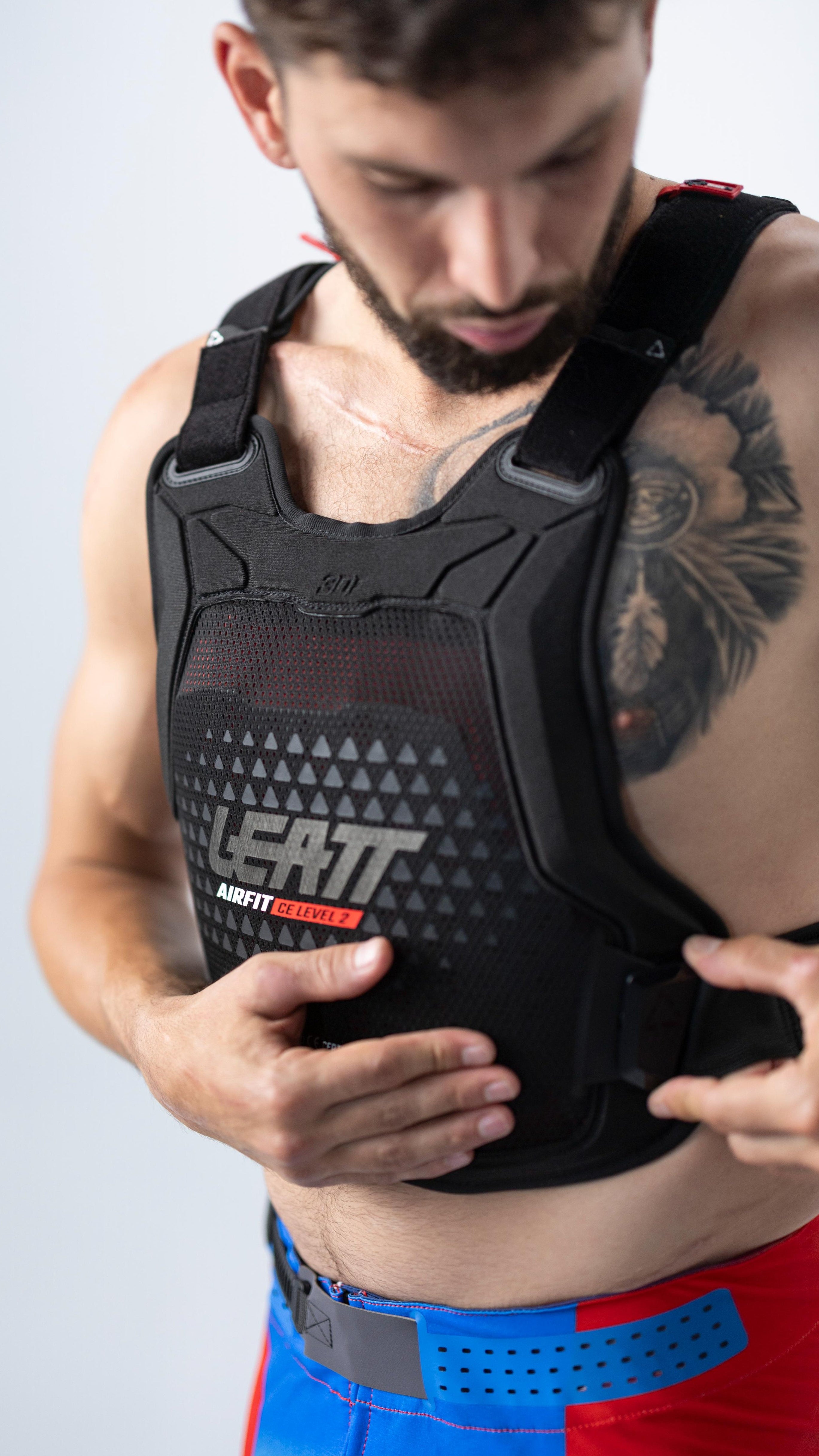 Man wearing a black Leatt protective vest on a light gray background