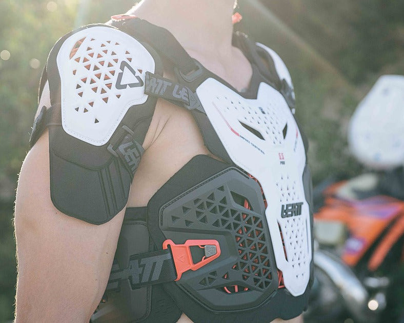 Person wearing a black and white Leatt motorcycle armor vest with a blurred background