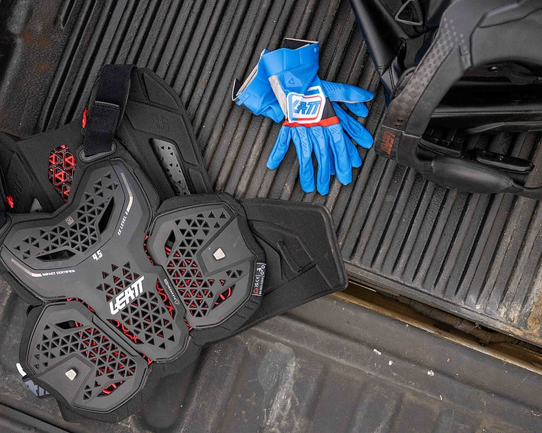 Black protective gear with red accents and blue gloves on a vehicle's open cargo area.