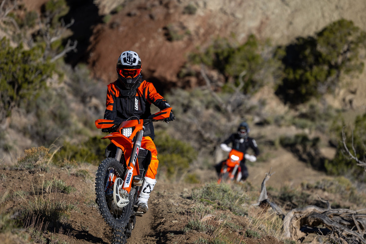 Two dirt bikers on a trail in a desert landscape