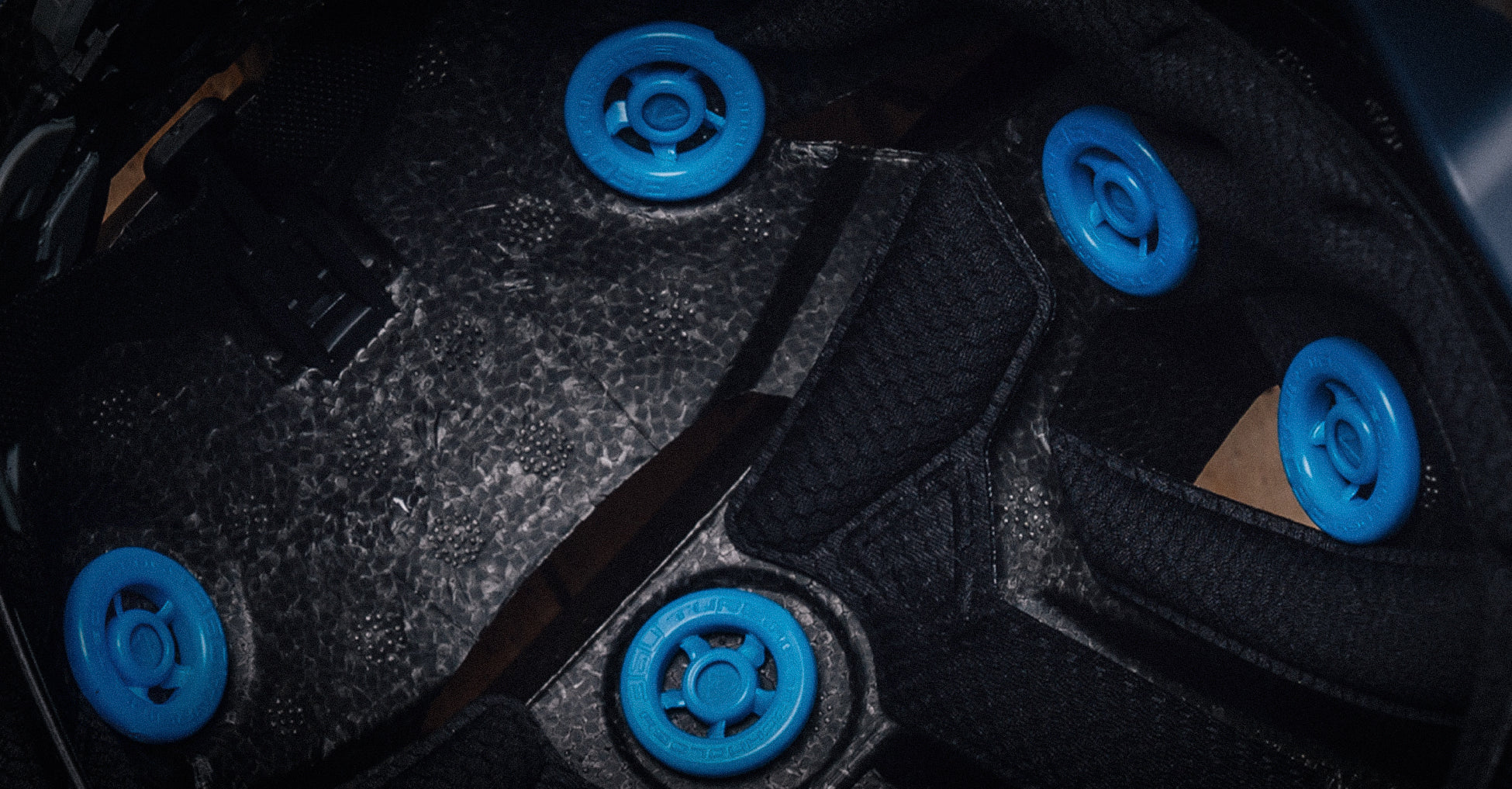 Close-up of a black textured helmet liner with five bright blue circular 360 turbines.