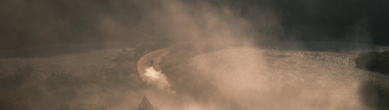 Dusty dirt road with a rider in the distance, evoking a sense of mystery and solitude.