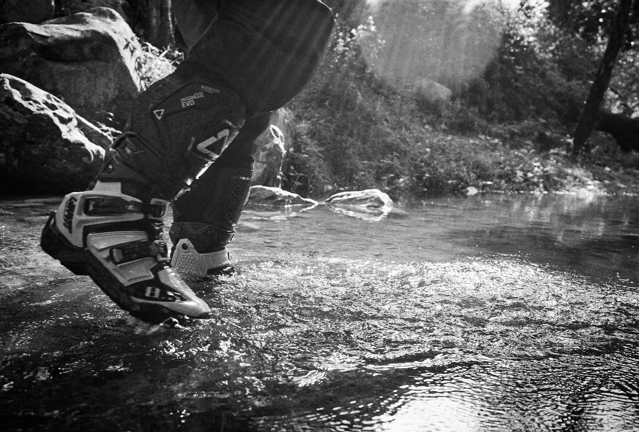 Person stepping into water with a ADV 8.5 boots, surrounded by nature