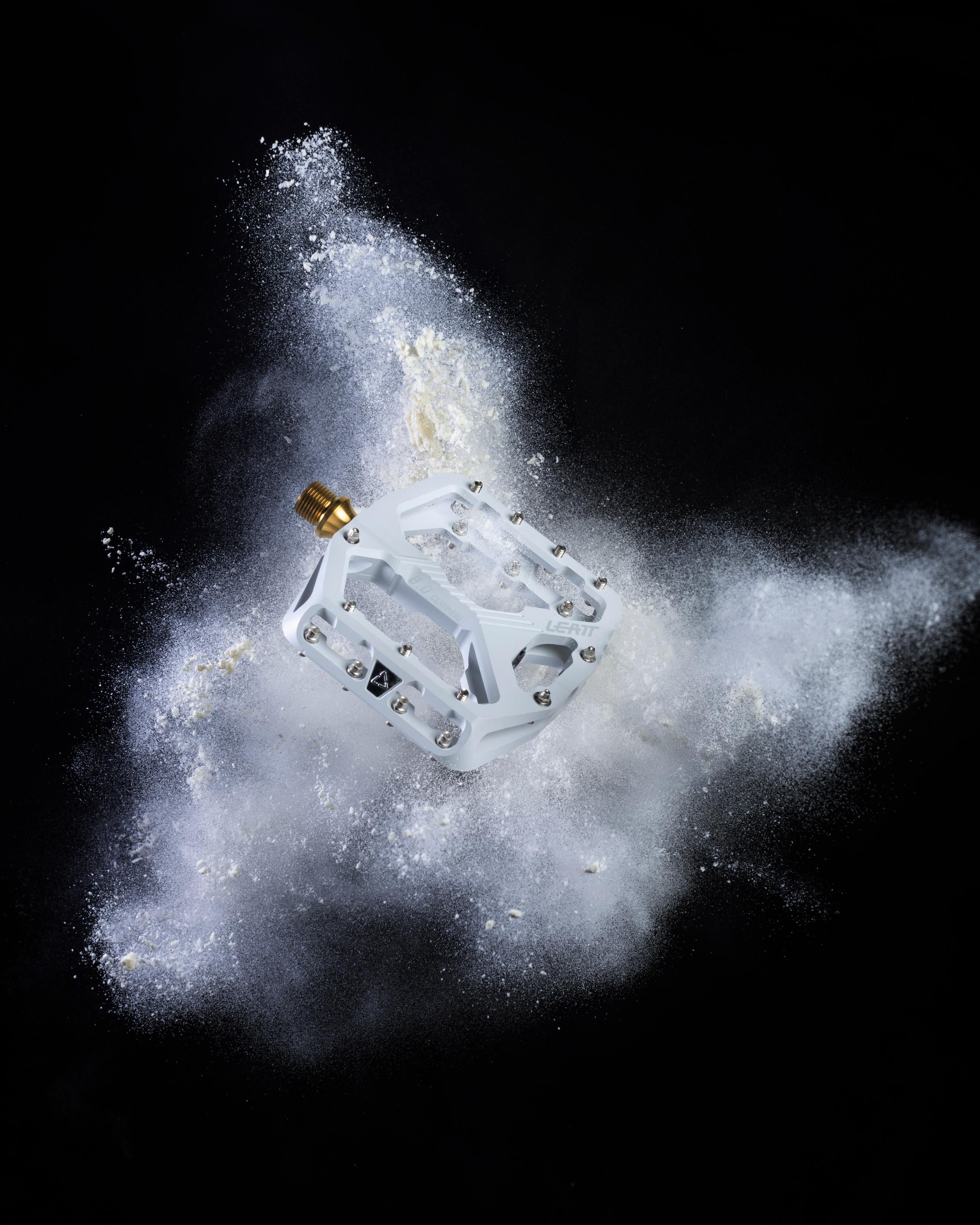 Pedal surrounded by a cloud of white powder against a black background