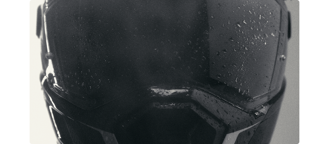 Close-up of a matte black motorcycle helmet with water droplets on the visor, set against a neutral light gray background.