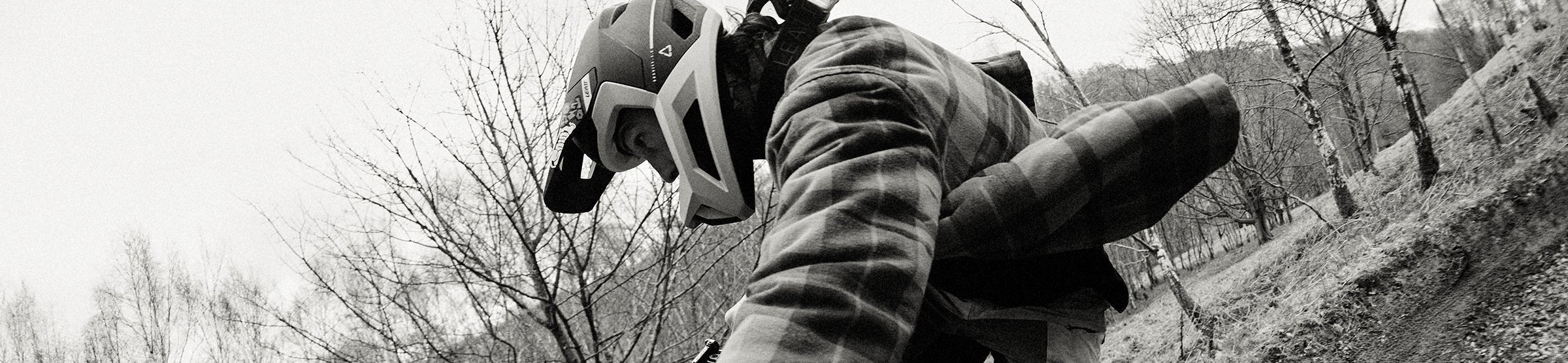 Person on a bike in mid-air performing a stunt with trees and grass in the background