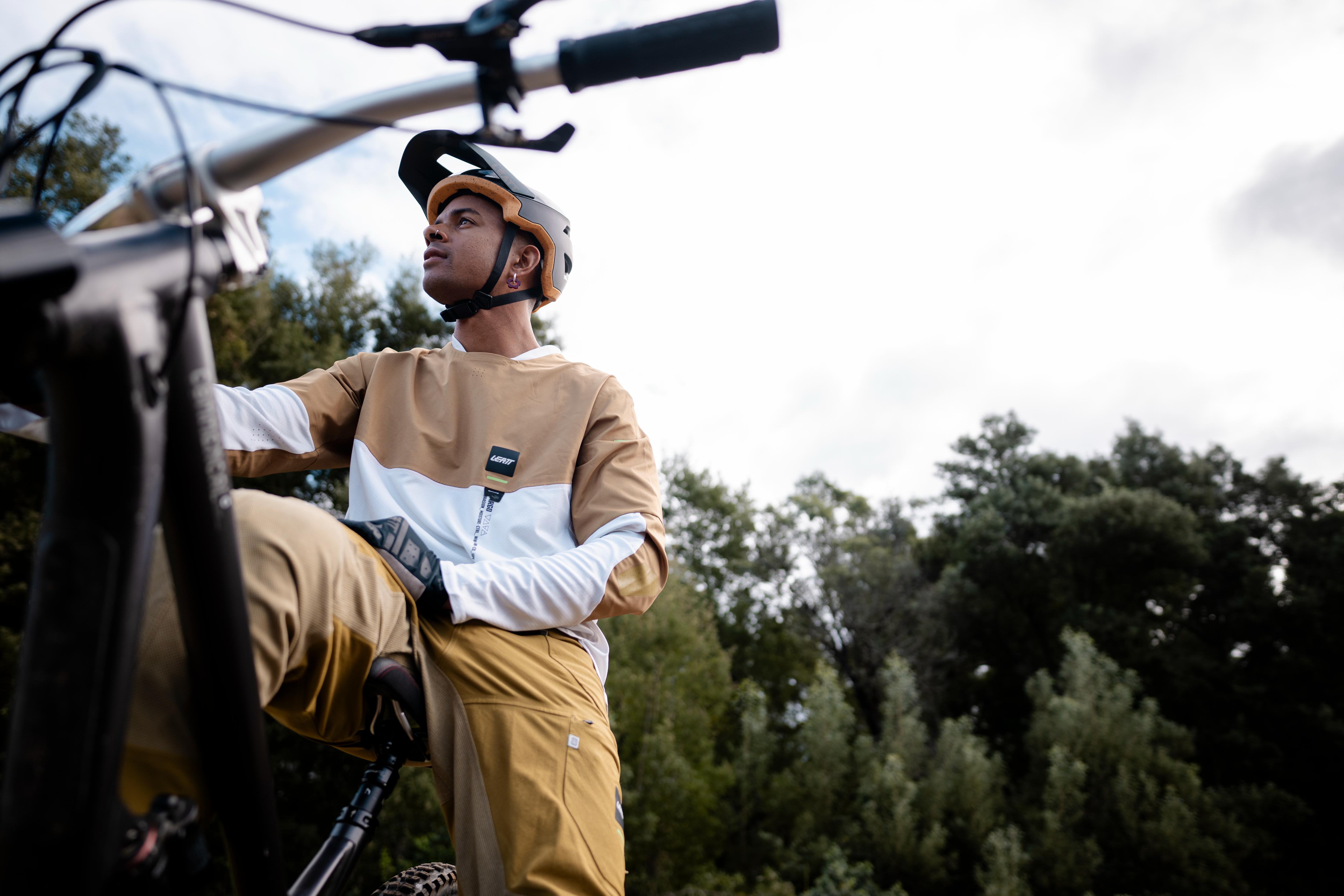 Person sitting on a bicycle with a helmet, surrounded by trees